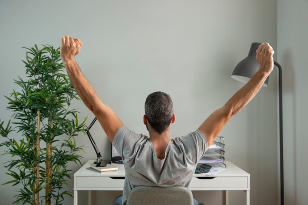 back-view-man-stretching-his-arms-while-working-from-home_23-2148806690